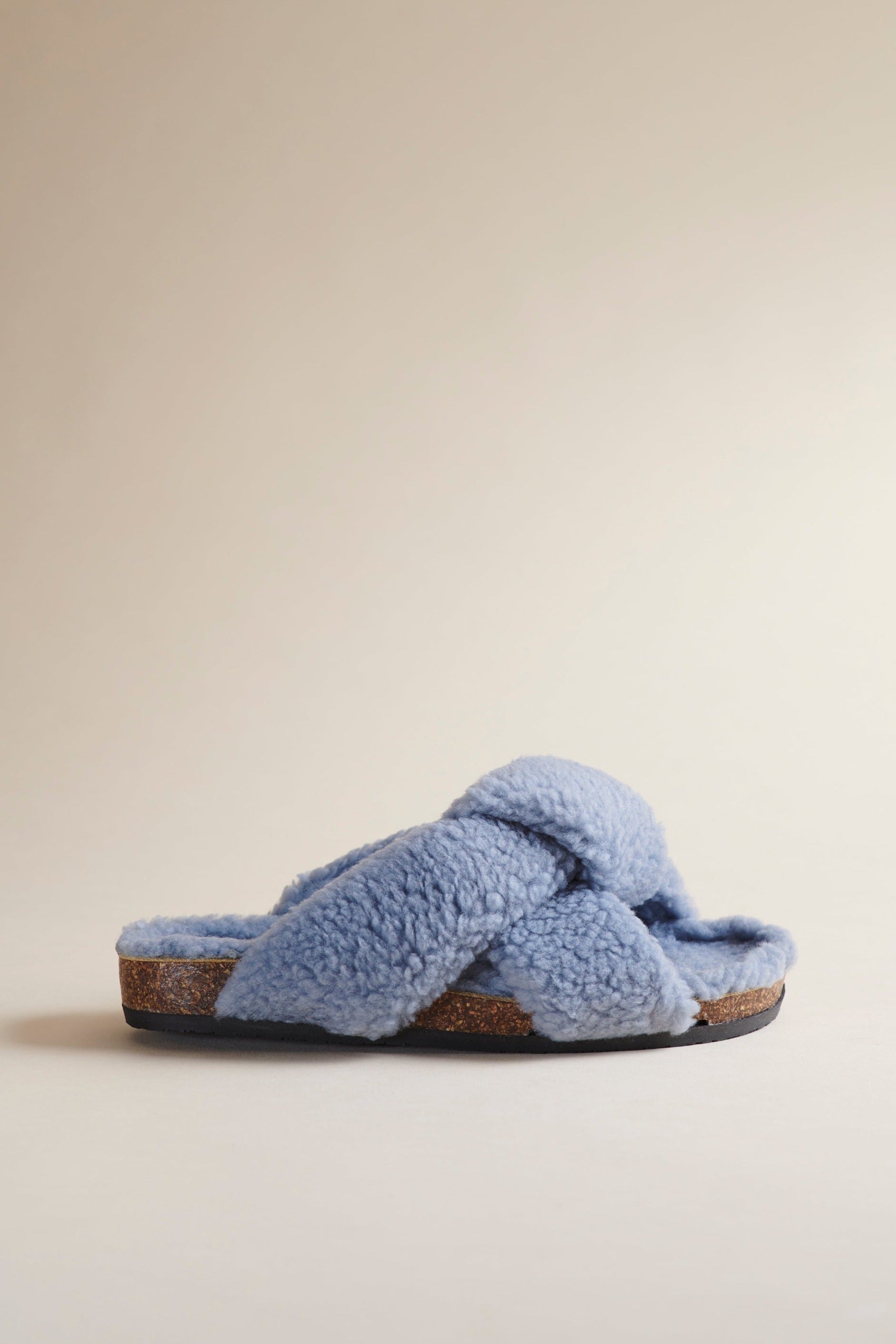 Brother Vellies Teddy Togo in Sky Blue is a shearling open-toed clog. Profile shown here on a beige background.