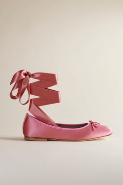 Brother Vellies Lalli Ballet flat in Candy Floss pink with a satin ribbon from the ankle, shown zig-zagging vertically and tie in a bow on a beige background.