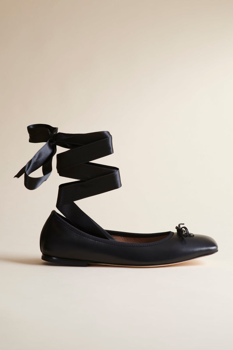 Brother Vellies Lali Ballet Flat in Midnight with silk ankle straps zig zagging up and tied with a bow. Show from the side against a beige backdrop.