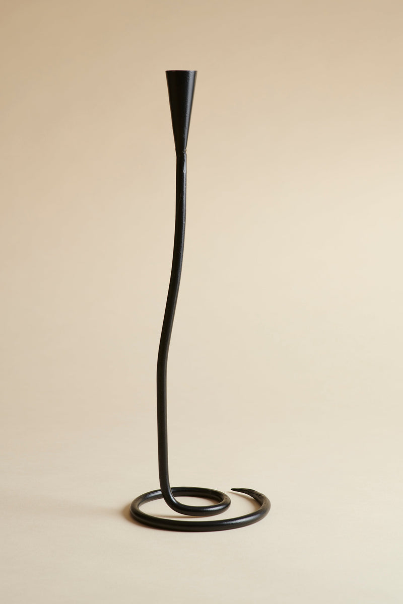 Black metal candle holder with a curved design on a beige background