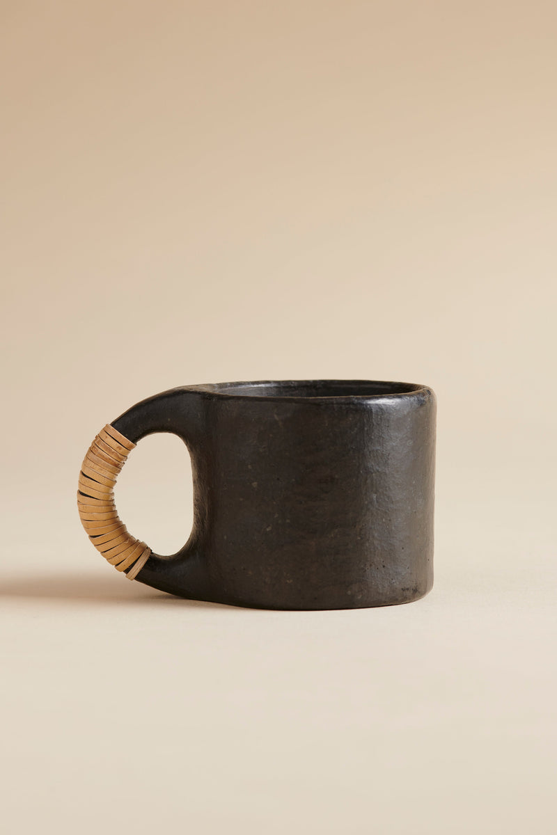 Black ceramic mug with a wooden handle on a beige background