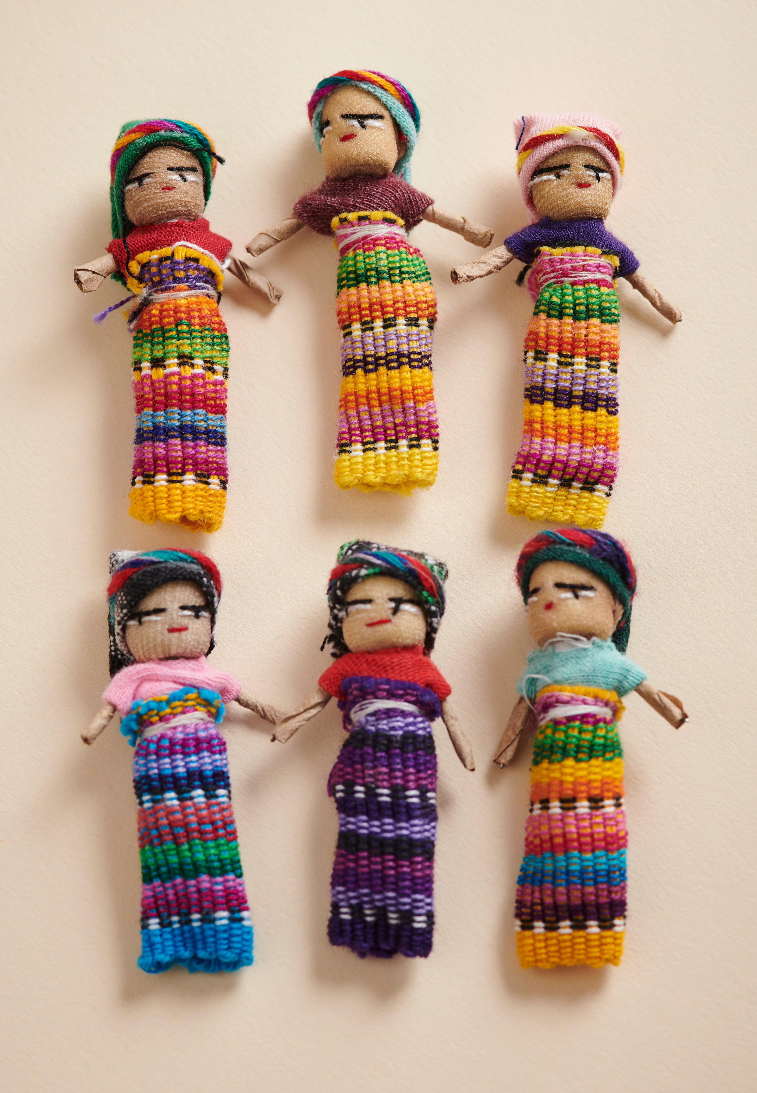 Set of colorful handcrafted dolls with traditional attire on a beige background