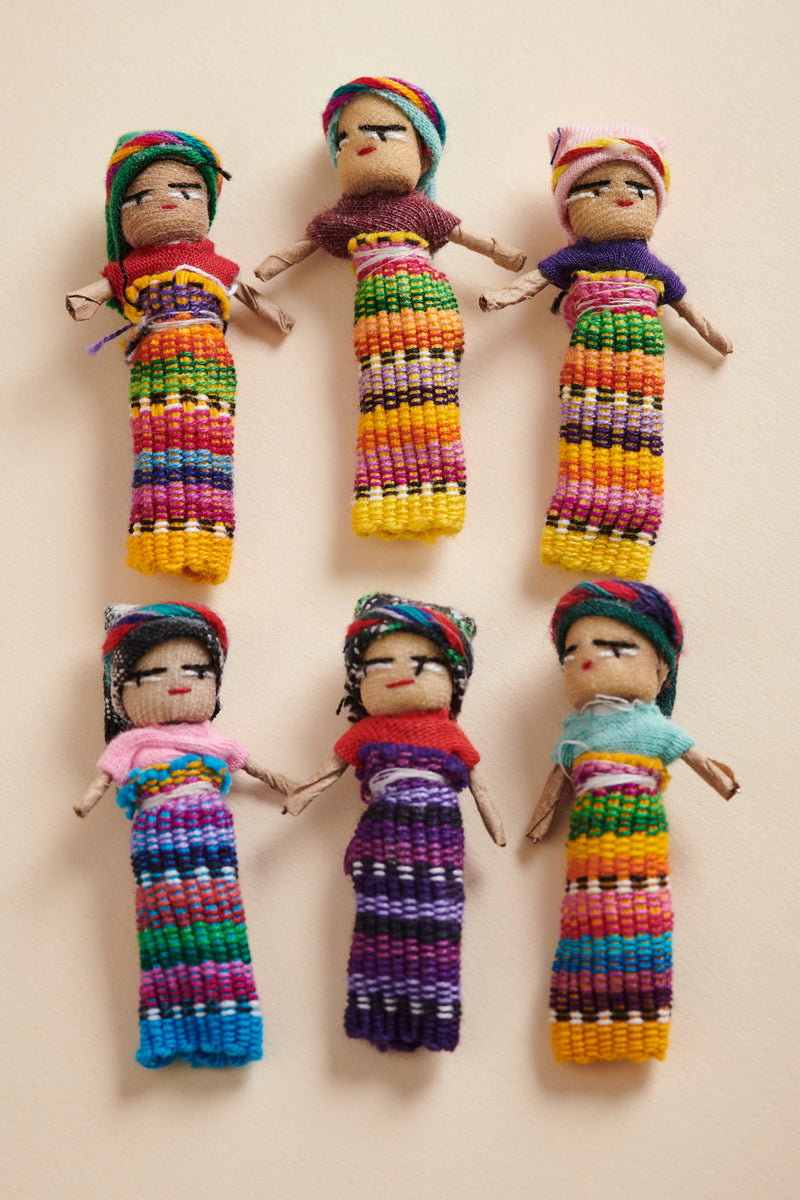 Set of colorful handcrafted dolls with traditional attire on a beige background
