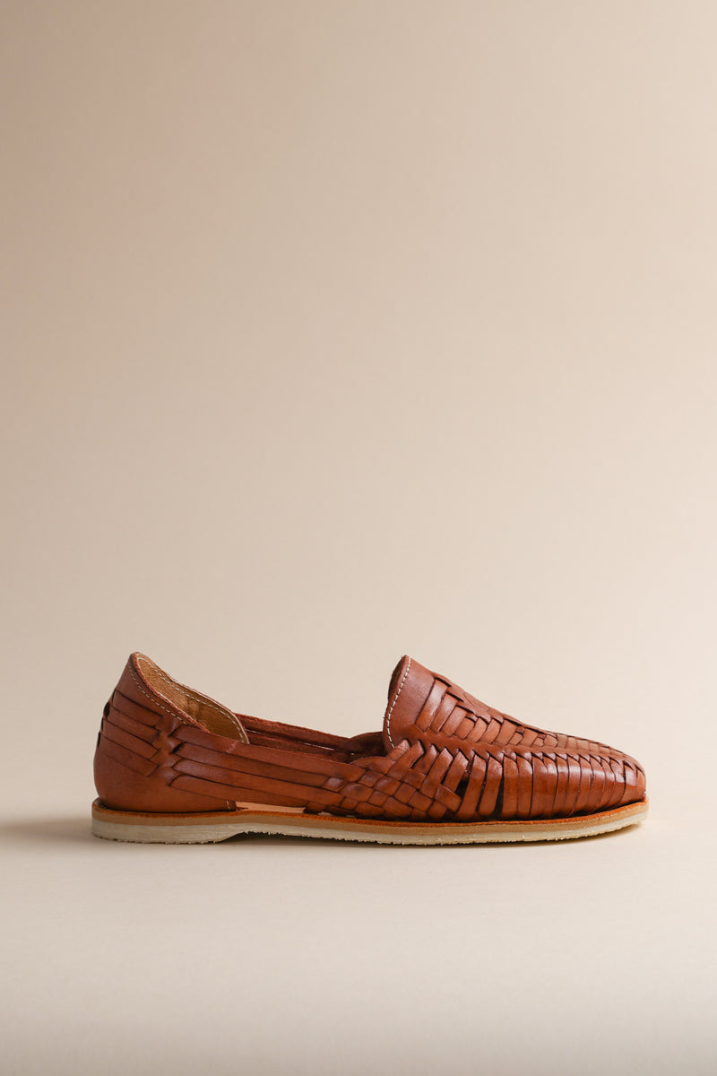 Brother Vellies brown woven huarache flat shoe on a beige background.